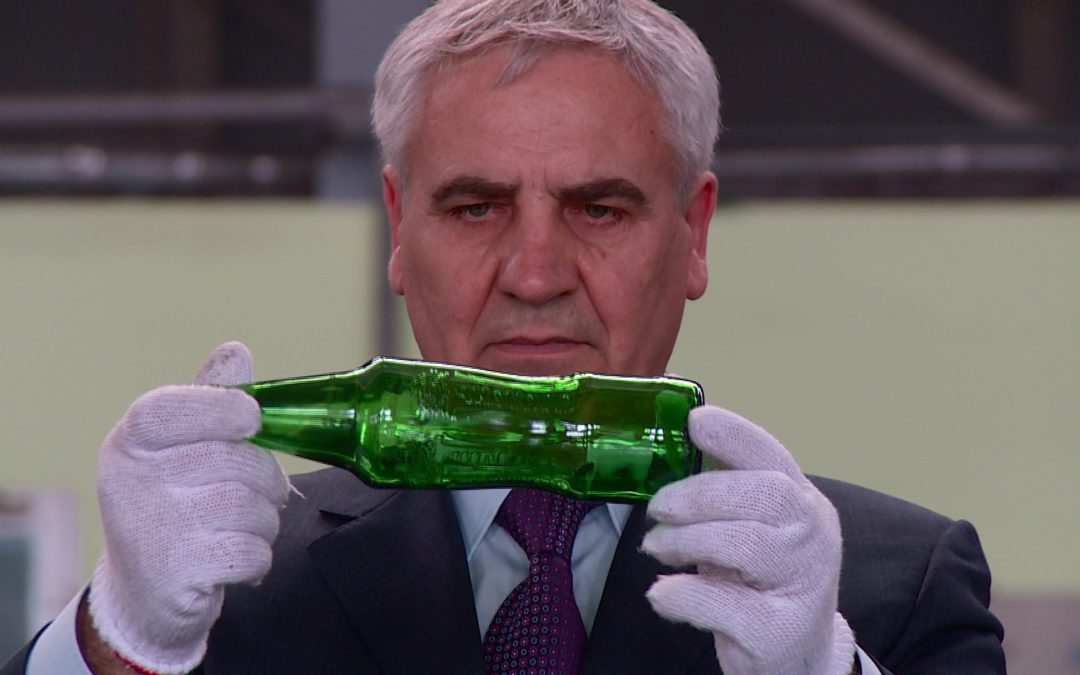 ein Mann hält eine Glasflasche in den Händen, die er betrachtet