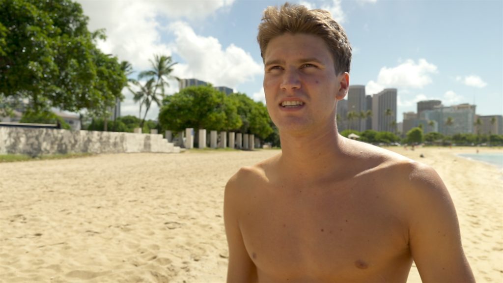 Foto von Schwimmer Romano Mombelli, der mit nacktem Oberkörper an einem Strand in Hawaii steht.