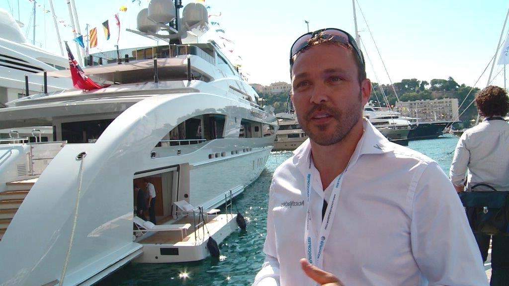 Mann in weissem Hemd steht vor Luxus-Yacht
